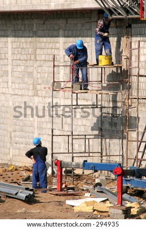 Bricklayers in safety helmets on scaffolding