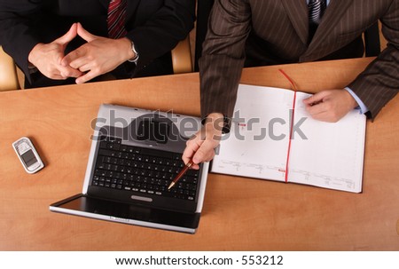 2 business men working at the desk with laptop and cell phone on