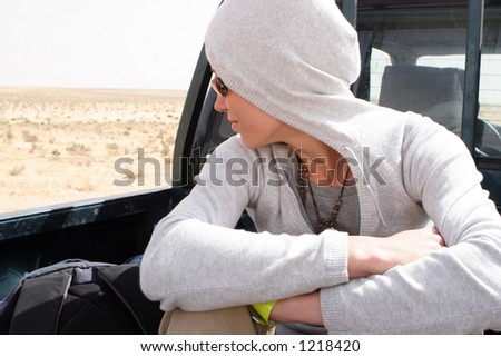 traveler woman in the hood going by truck on dessert - profile