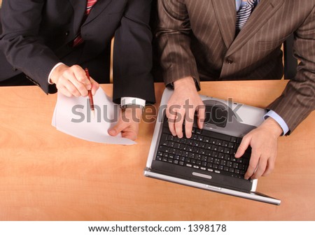 2 businessmen with laptop and blank paper sitting at the desk - no heads included...