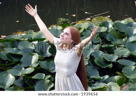 Young happy woman in long dress rises hands to heaven - outdoor