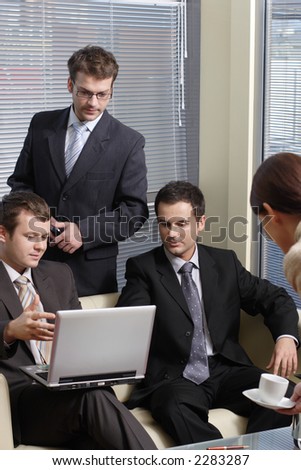 secretary serving cup of coffee to young business men in the office