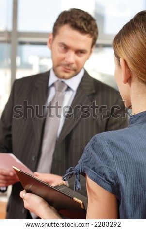 business man talking to business woman in the office - man out of focus