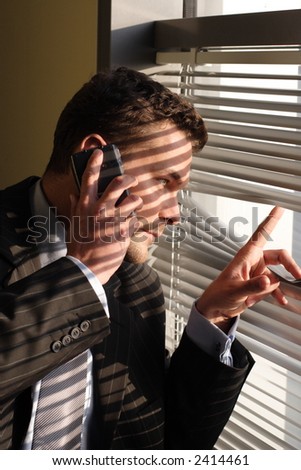 Handsome  calling on phone secret man looking through window blinds