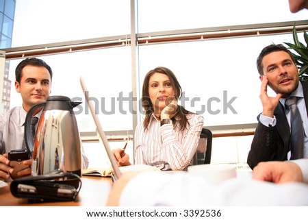 A group of four business people gather around a conference room table for a working discussion to plan a new project.