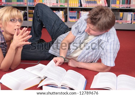 male and female students reviewing material from the books in the library