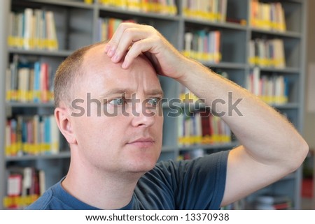thinking balding man close up - bookshelf in background