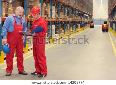 standing workers in warehouse reading invoice