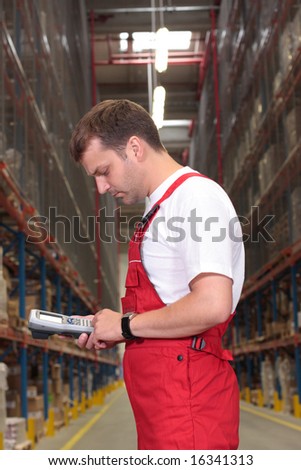 A worker with scanner in a factory looking at stocks of finished products on the shelves in a storeroom.