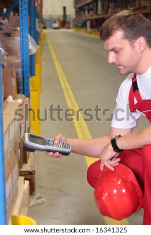 A worker with scanner in a factory maintaining stocks of finished products on the shelves in a storeroom.