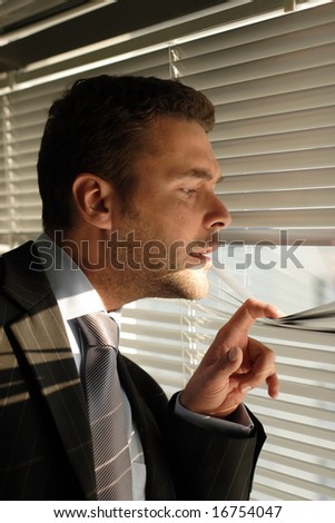 business man looking through window blinds