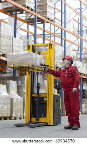Senior,experienced worker in red uniform with bar code reader working in warehouse
