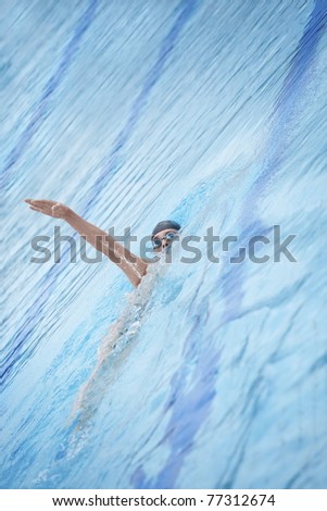 Swimmer in goggles and cap swimming back crawl