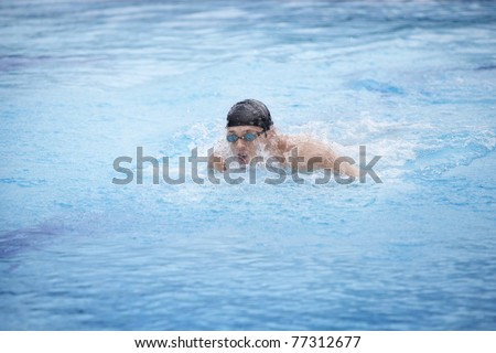 Swimmer in cap and goggles taking breath in swimming pool