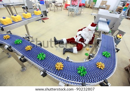 Tired overworked santa claus lying on the floor at the  presents production line in factory