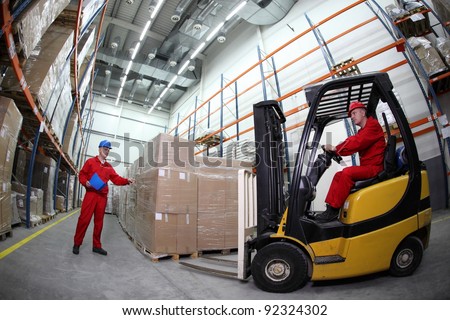 goods delivery in storehouse, two workers  reloading pallets  with  forklift truck
