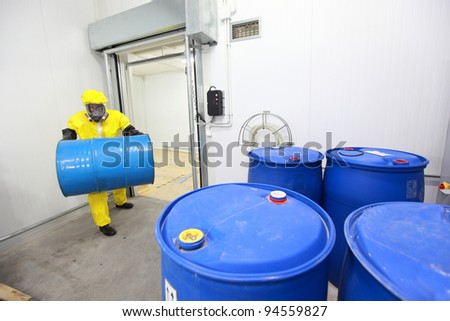 Worker in protective uniform,mask,gloves and boots  carrying barrel of chemicals