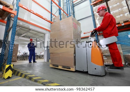 Goods delivery - two workers  with forklift loader working in storehouse