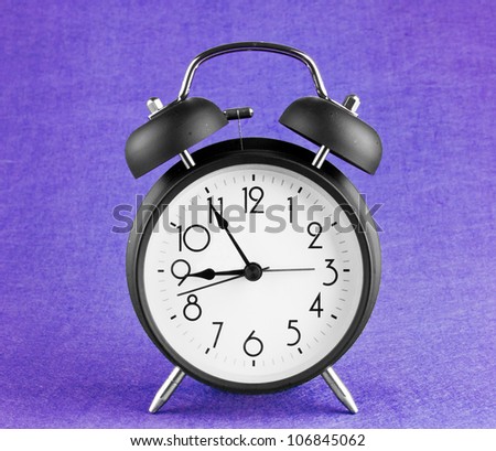 Old-fashioned alarm clock isolated on a purple background