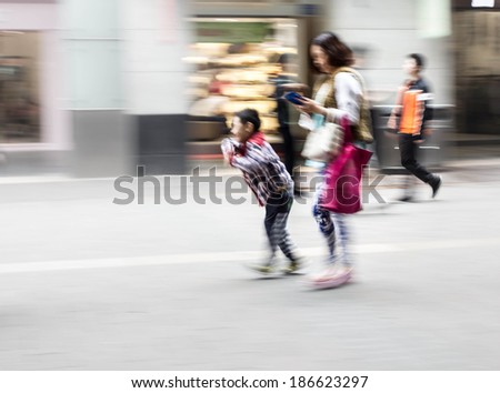 Mother with children walking in urban commercial street, blurred motion background