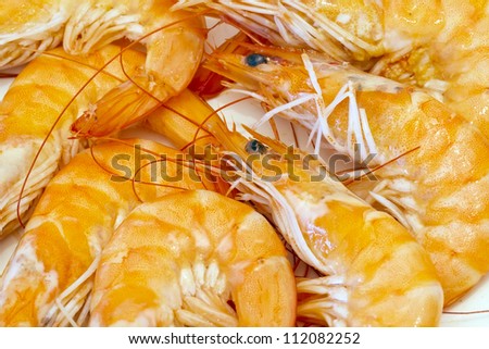 Pile of cooked and peeled shrimp. Detail of the heads and eyes of this seafood. Presented in plate