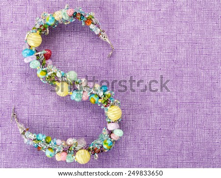 S-shaped glass beads necklace on purple background