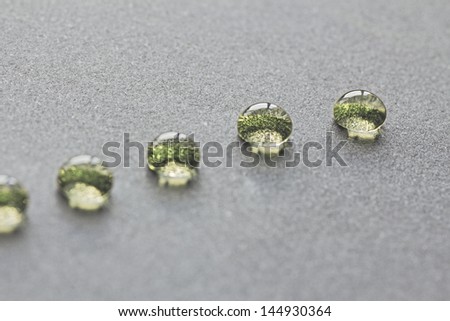beautiful green water drops in a row, on grey background