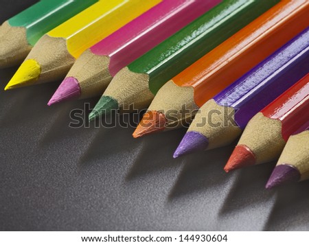 colored pencils aligned in a row, a full color palette, against dark background