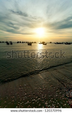 fishing boats in the evening on water, the gold sun on the horizon