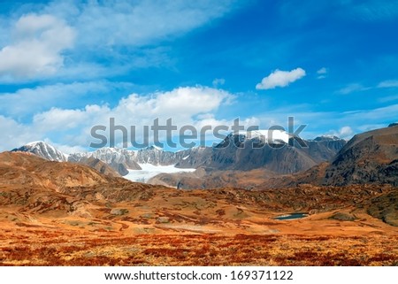 snow mountain tops with the blue sky and the yellow desert