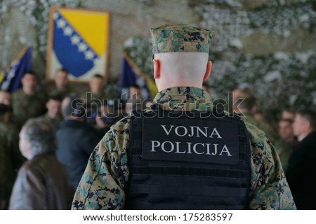 Bosnian Military officer protects a group of people