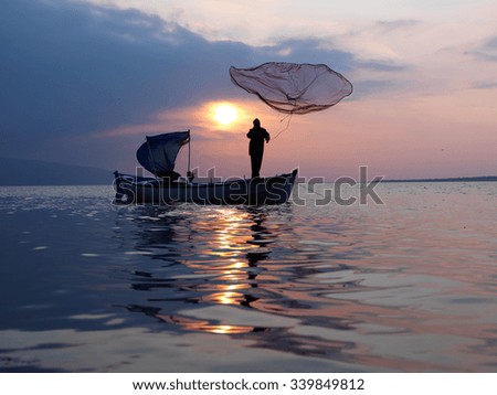 fisherman throwing nets to sea at sunset time