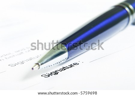 Signing a contract. Focus is on the signature and the end of the pen.
