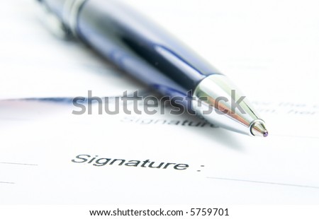 Signing a contract. Focus is on the signature and the end of the pen.
