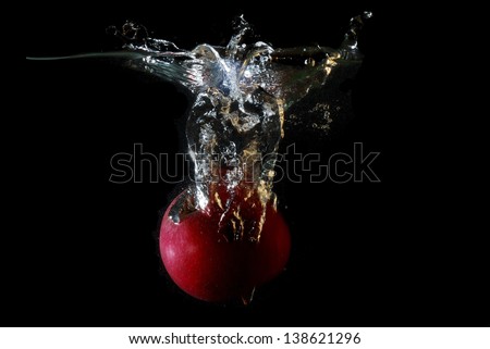 fresh healthy red apple falling into water and splashing and making bubbles on black background