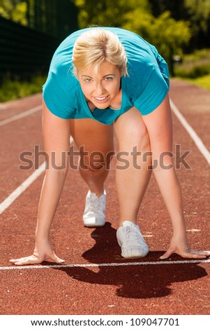Young woman at the start of a race in athletics / On your marks go