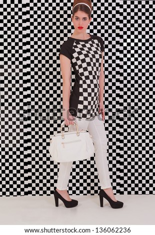 dressed young model with trendy Italian fashion in black and white and bag in hand / Ultimate luxury starts here