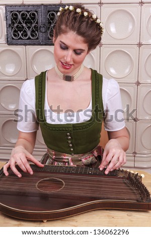 Young Bavarian girl in traditional dress plays music on a zither / Play Young Bavarian girl in Zither