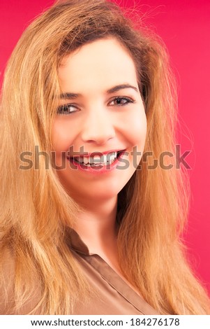 Portrait of a beautiful laughing woman with long blond hair, with overweight and beautiful teeth with red background / Portrait of a beautiful laughing woman with long blond hair