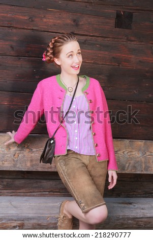 Happy female model with views up and short Bavarian leather pants and pink cardigan. / Happy Female Model Looking Up