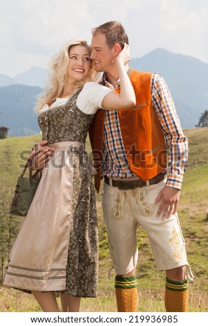 Young romantic couple in traditional Bavarian costumes look at love. / Young romantic couple in traditional Bavarian costumes
