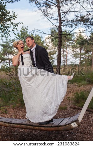 Young married couple is frivolous on a large swing, thereby covering his bride at his tie firmly. / Young married couple is frivolous on a large swing.