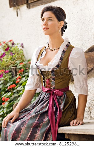 Young Bavarian operation served a glass of white beer / Young woman in dirndl with white beer