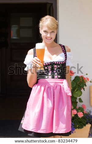 Young woman in dirndl wheat beer served in a mountain economy /Young woman in dirndl with white beer