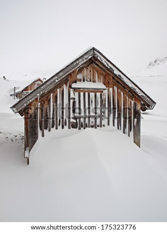 Small alpine cabin and snow drift