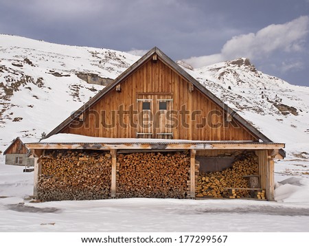 Agricultural building with wood pile in a wintry alpine landscape