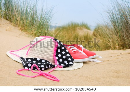 bikini, sun hat and shoes in sand dunes on beach