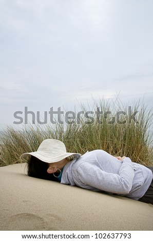 woman asleep on beach with sun hat over face