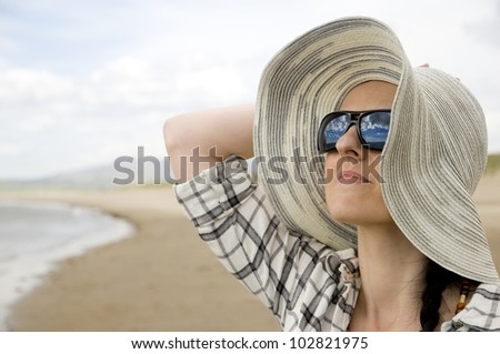 woman on beach with sun hat and glasses