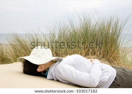 woman asleep on beach with sun hat over face landscape